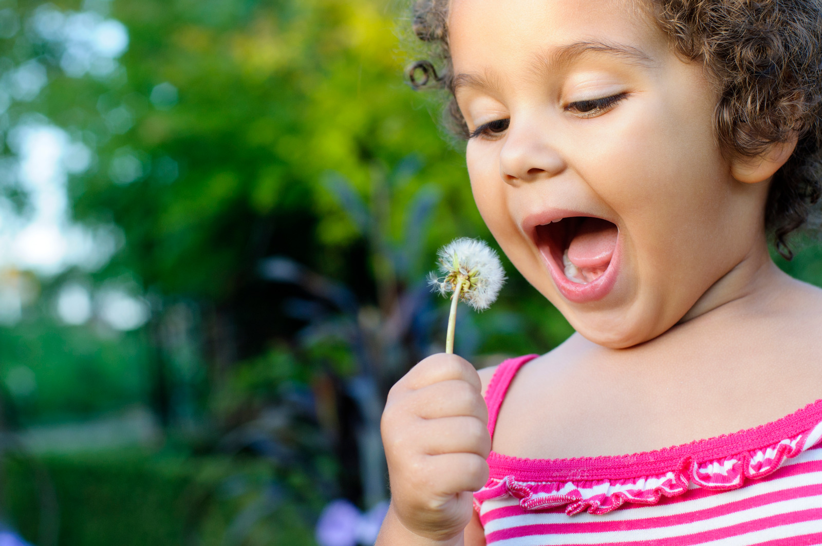 une petite fille qui souffle sur une fleur